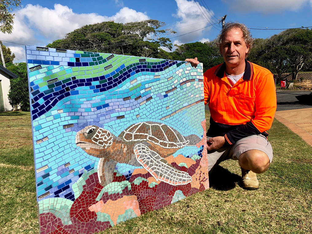 Paul Perry and his original mosaic artwork that now sits on the wall of the public amenity block at Archies in Bargara.