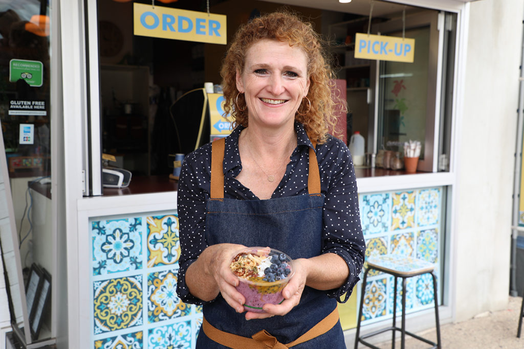 Owner Judy Plath outside Street Bean Coffee Bar with a smoothie bowl.