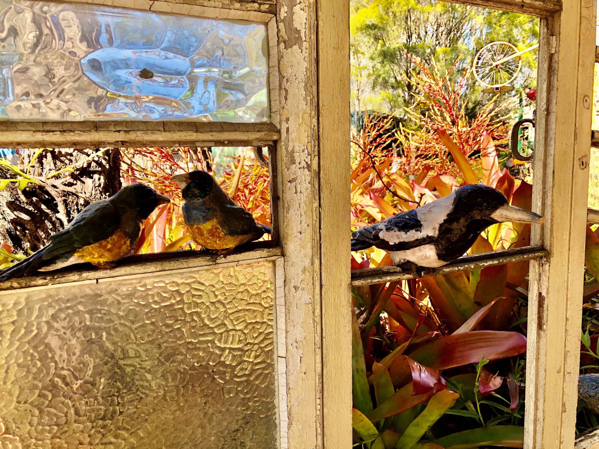 Ceramic birds make a lifelike scene as they perch on a window opening into Alice McLaughlin’s gardens.