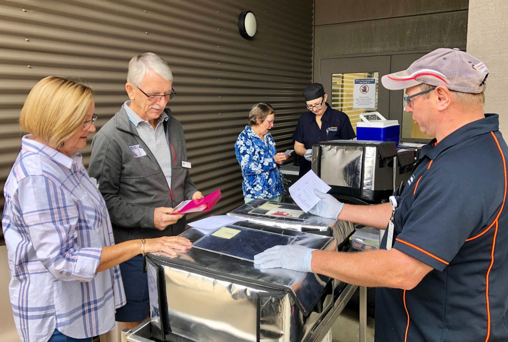 Gin Gin Hospital kitchen staff members Michael and Del assist Thelma Jensen and Wendy and Rhys Davies to pack their vehicles with meals for distribution.