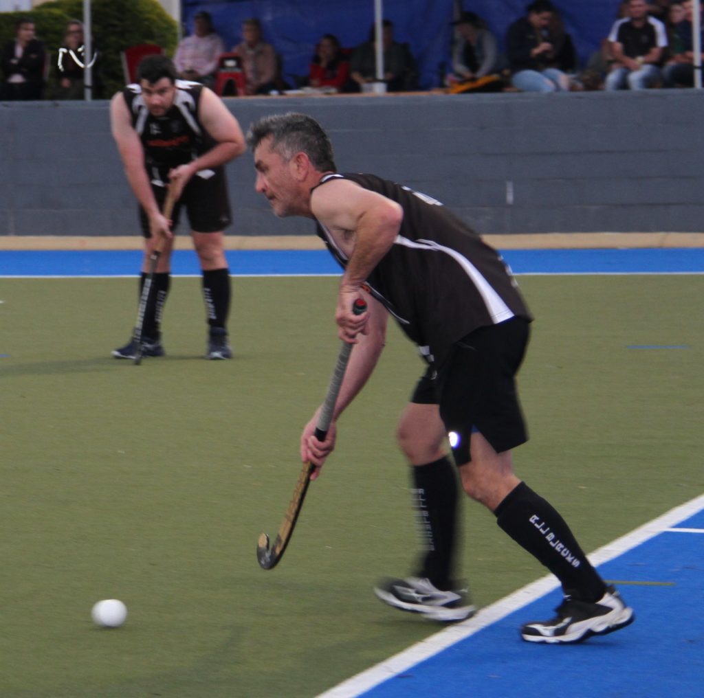 Peter Austin plays the ball for All Blacks in the Bundaberg Hockey men's grand final
