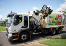 Garbage truck collecting waste and recycling bins.